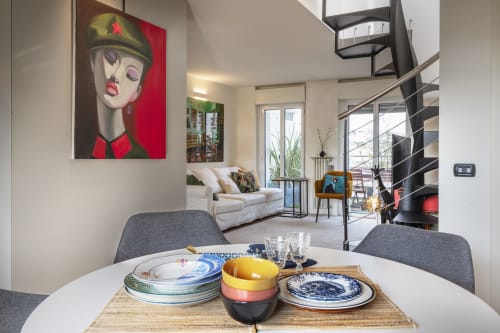 Zona pranzo dell'appartamento moderno a Milano con stoviglie colorate, scala a spirale e decorazioni pop art al GIRESIO 41 B&B