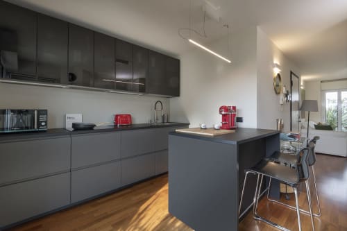 Cucina moderna con mobili grigi, isola con sedute e pavimento in legno nell'appartamento GIRESIO 41, Milano
