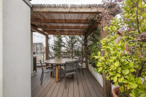 Terrazza esterna dell'appartamento GIRESIO 41 a Milano con pavimento in legno, tavolo da pranzo, pergolato e vista sulla città