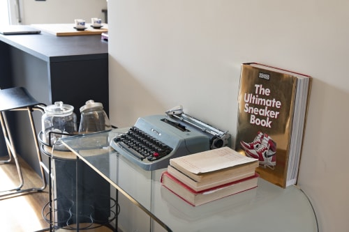 Scrivania moderna in appartamento milanese con macchina da scrivere, libri, macchinetta del caffè e sneaker in esposizione