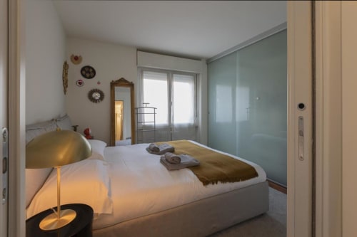 Camera moderna della GIRESIO 41 Milano BnB con letto, lampada dorata, piatti decorativi e armadio in vetro