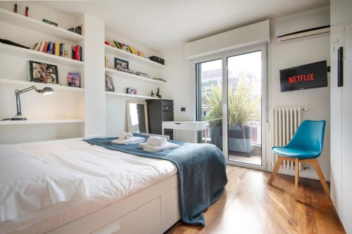 Camera moderna del GIRESIO 41 Milano BnB con letto bianco, accenti blu, scaffali e vista sul balcone