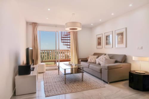 Moderna sala de estar del hotel SACORO en Marbella con sofá gris, vistas al balcón y mobiliario contemporáneo