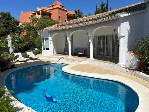 SACORO, lujosa piscina en Marbella con alberca curva, patio blanco abovedado y villa de terracota