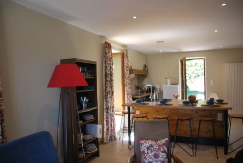 Cuisine-salle à manger contemporaine du Château de Vaux Morvan avec comptoir en bois, lampe rouge et rideaux à motifs