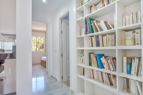 Pasillo moderno de apartamento con estanterías blancas empotradas, acceso al dormitorio, apartamento SACORO Marbella con vistas al mar