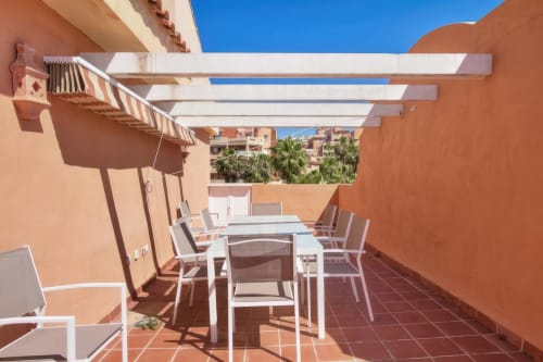 Amplia terraza del apartamento SACORO en Marbella con mesa de comedor, tumbonas, pérgola y vistas al mar