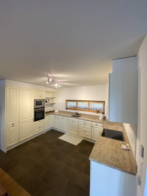 Cuisine moderne de l'appartement Grangette Villars avec armoires crème, comptoirs en granit et vue sur les montagnes