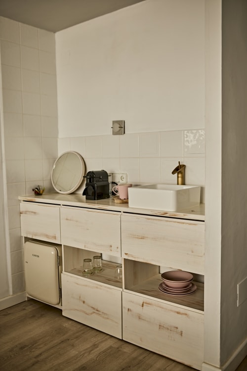 Lavabo minimalista con muebles blancos, lavamanos de cerámica y grifo de latón en el hotel Formentera Especial, La Savina