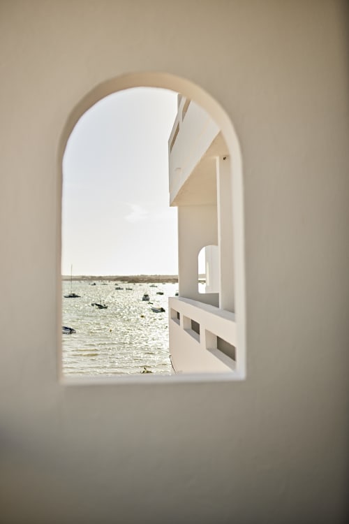 Ventana blanca arqueada enmarando vista al mar con barcos amarrados en el hotel Formentera Especial, La Savina