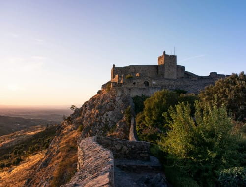 Medieval castle ruins on rocky hilltop at sunset overlooking Juromenha, Portugal countryside