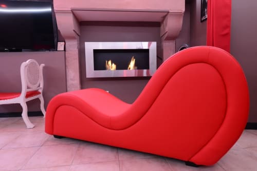 Red sculptural lounge chair with fireplace in romantic Love Room at Les Secrets de Winna boutique hotel
