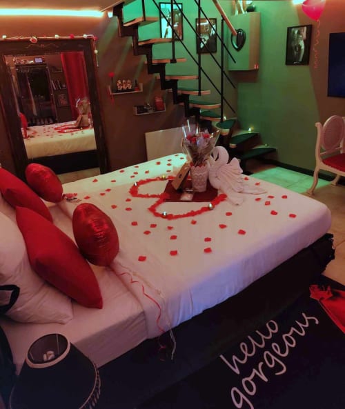 Romantic bedroom with heart-shaped rose petals, red pillows, and candles at Les Secrets de Winna love room in Deux-Sèvres,