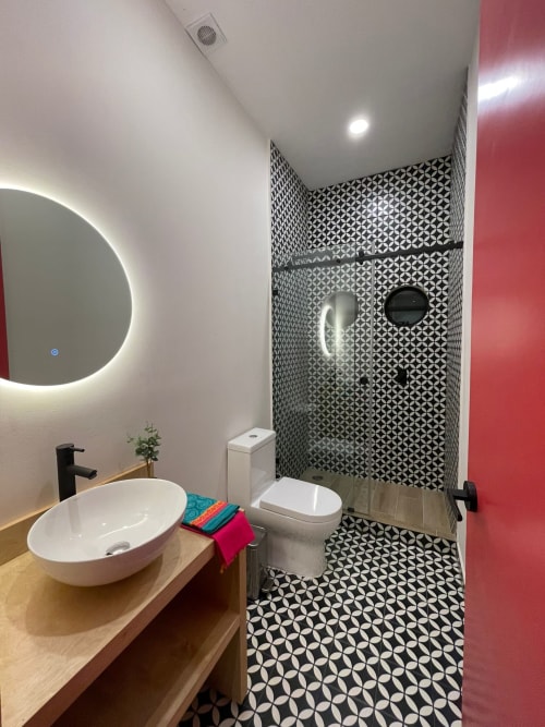 Baño moderno en Casa Donceles con azulejos geométricos en blanco y negro, lavamanos tipo vasija, espejo iluminado y ducha abierta