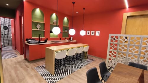 Cocina y comedor del moderno apartamento Casa Donceles con paredes rojas, baldosas geométricas, lámparas colgantes y asientos