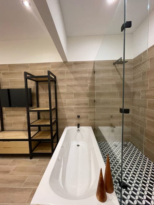 Baño moderno en Casa Donceles con bañera blanca, paredes de azulejos imitación madera, piso de azulejos geométricos y ducha con cristal