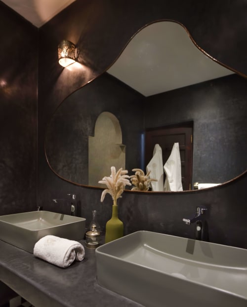 Moderne badkamer in Chambre Royale van Riad Palau Marrakech met dubbele wastafel, gebogen spiegel, donkere muren en witte handdoeken