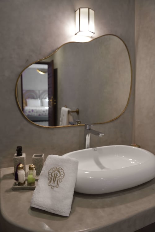 Luxe badkamermeubel in Riad Palau Marrakech met designspiegel, wit opzetbekken en gemonogrameerd handdoek