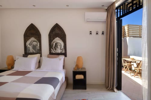 Slaapkamer Riad Palau Marrakech met Marokkaanse gewelfde spiegels, witte beddenlinnen, geweven accenten en terrastoegang