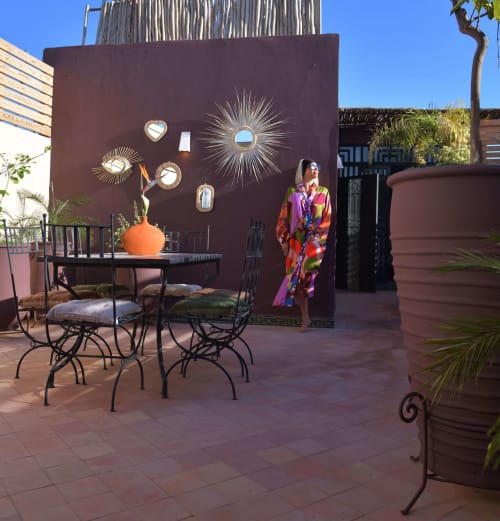 Marokkaanse riad-binnenplaats met eettafel, decoratieve muurschildering en vrouw in kleurrijke kaftan in Riad Palau Marrakech