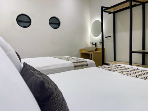 Dormitorio moderno en apartamento Casa Donceles, Ciudad de México, con dos camas, ventanas circulares, tocador de madera y marcos negros