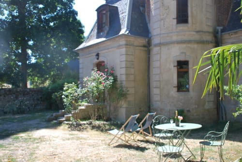 Château de Vaux Morvan's courtyard garden with loungers and dining table near stone manor house in Étang sur Arroux, France