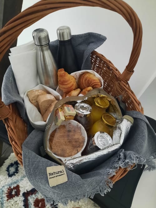 Panier en osier avec croissants frais, pain, huile d'olive, bocaux et thermos à la Maison Rinette, chambre d'hôtes à Dijon,