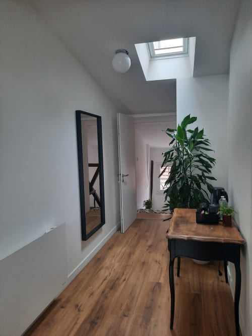 Chambre mansardée moderne à la Maison Rinette Dijon avec lucarne, parquet, miroir, bureau et plante en pot