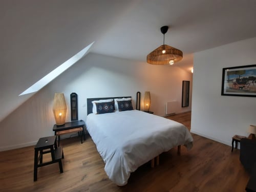 Chambre mansardée moderne à la Maison Rinette, Dijon avec puits de lumière, parquets, éclairage suspendu et mobilier contemporain.