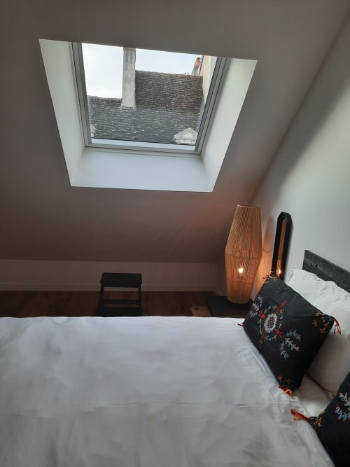 Chambre Maison Rinette à Dijon avec vue sur les toits ardoisés, linge blanc, lampe en bois et panorama urbain