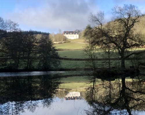 Château de Vaux Morvan se reflétant dans un étang, entouré d'arbres et de prairies verdoyantes à Étang sur Arroux, France
