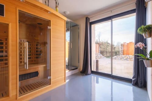 Spa avec sauna en bois et porte vitrée à la villa Domaine du Haut de la Dombes, vue sur le jardin