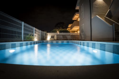 Piscina esterna illuminata di Residence Balconi del Conero a Marcelli con moderna struttura e dettagli in piastrelle blu di notte