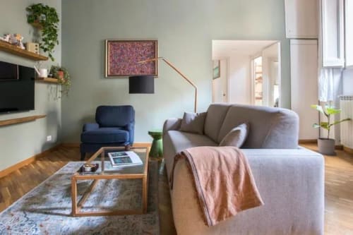Salotto moderno a Roma con divano grigio, tavolo in legno, poltrona blu e vista sulla città vicino a Campo de' Fiori