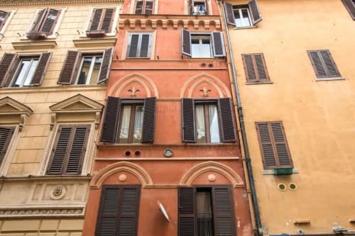 Affascinante facciata storica colorata a Roma vicino a Campo de' Fiori con finestre ad arco e persiane in legno