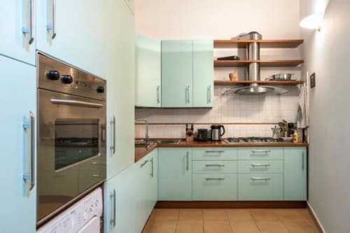 Cucina moderna verde menta con banconi in legno, elettrodomestici in acciaio inox e scaffalature aperte nell'appartamento di Roma