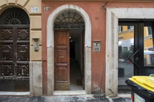 Ingresso di storico edificio rosso con porta in legno vicino a Campo de' Fiori, affitto appartamento Roma
