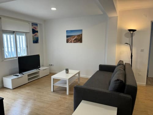 Sala de estar moderna no Apartamento Jorge em Sintra Apartamentos com sofá cinzento, TV, pisos em madeira e obra de arte de paisagem