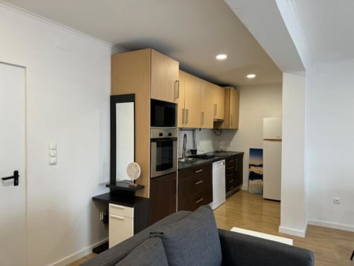 Cozinha e sala de estar modernas no Apartamento Jorge em Sintra Apartamentos, com armários de madeira e aço inoxidável