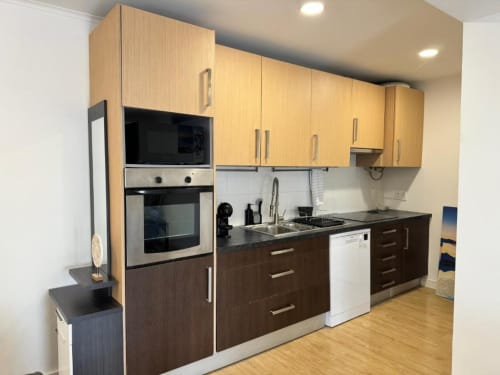 Cozinha moderna do Jorge Apartment em Sintra Apartamentos com móveis em madeira clara, armários inferiores escuros e aço inoxidável