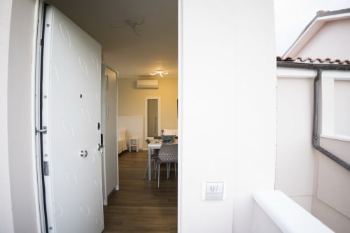 Studio apartment entryway with white doors, wooden flooring, and kitchenette at Residence Balconi del Conero, Marcelli