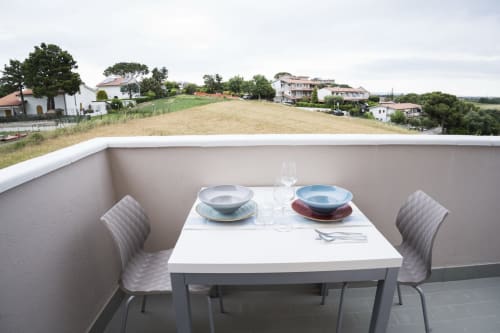 Balcony dining setup at Residence Balconi del Conero with table set for two, overlooking countryside landscape in Marcelli,