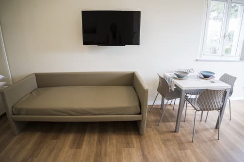 Modern apartment living area with sofa bed, dining table, flat-screen TV, and wood flooring at Residence Balconi del Conero