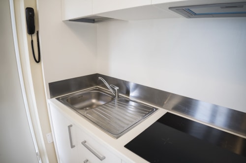 Angolo cottura moderno con lavello in acciaio inossidabile, piano cottura nero e mobili bianchi nell'appartamento Residence Balconi del Conero