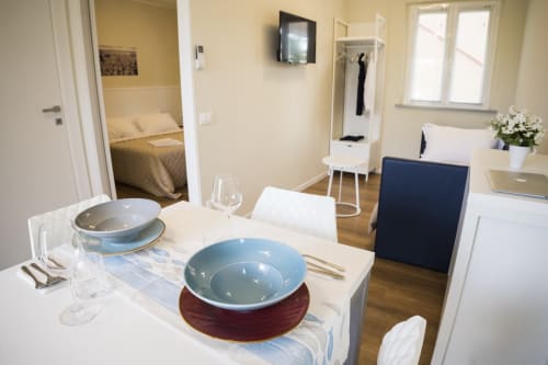 Elegante zona living con tavolo da pranzo, ciotola blu, angolo cottura, camera da letto e vista sulla corte interna della Residence Balconi