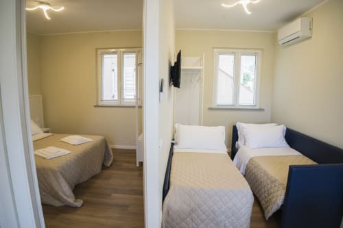 Camera moderna alla Residence Balconi del Conero con letti gemelli, pareti gialle, pavimento in legno e finestre con