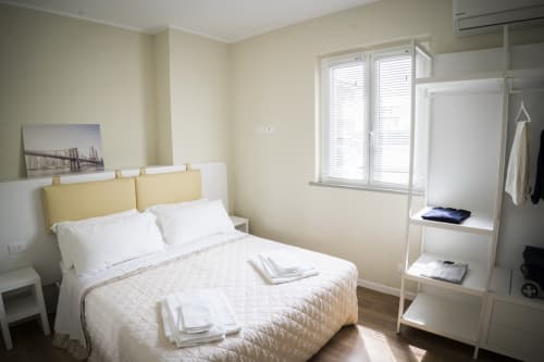 Bright bedroom at Residence Balconi del Conero with queen bed, yellow headboard, and modern furnishings overlooking inner