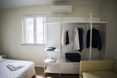 Modern bedroom at Residence Balconi del Conero with bed, white wardrobe, hanging clothes, and window with shutters
