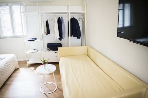 Bright apartment room at Residence Balconi del Conero featuring yellow sofa, wardrobe, TV, and wooden flooring.