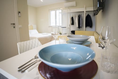 Elegant dining setup in Residence Balconi del Conero apartment with blue bowls, place settings, and bedroom view